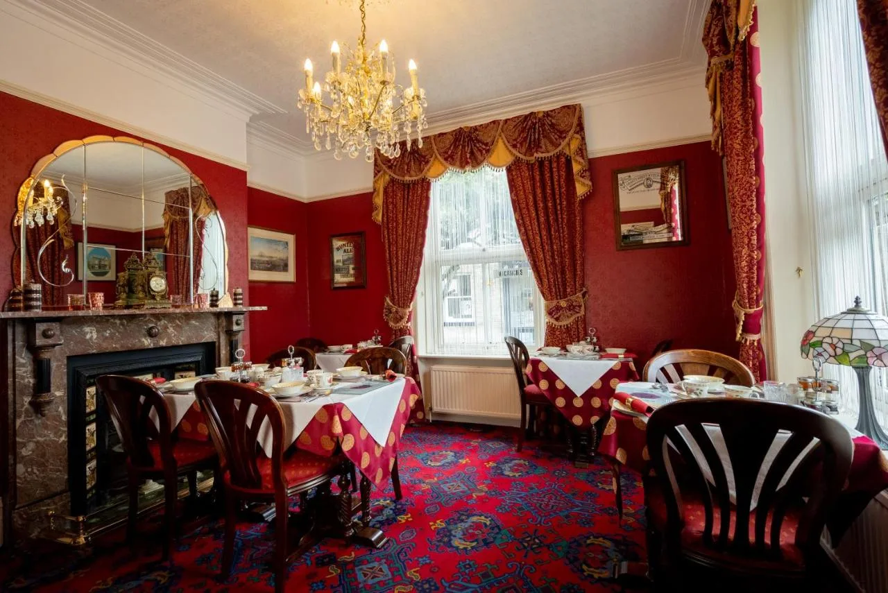 a dining room with red walls and tables and a chandelier at Barbican House in York
